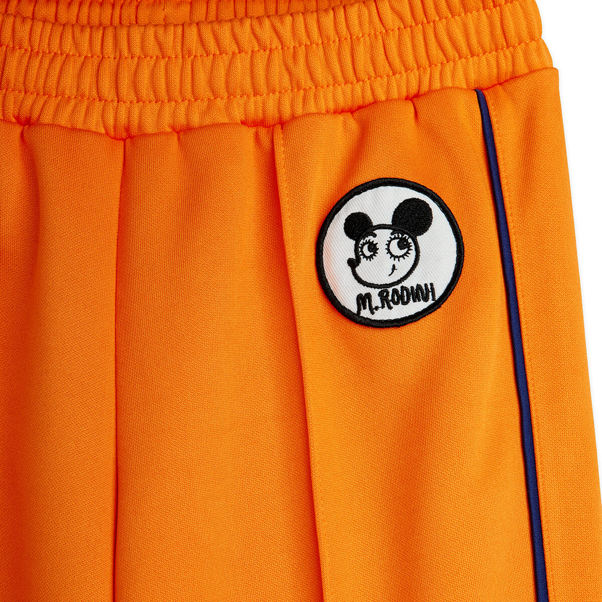 Pantalon en polyester recyclé sportif orange à imprimé patchwork, avec taille élastiquée et pli marqué sur le devant pour enfant